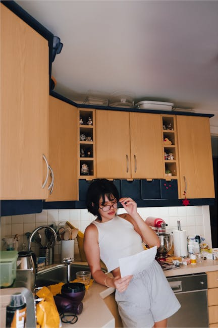 Young woman examining a document in a modern kitchen, surrounded by kitchenware and decor.